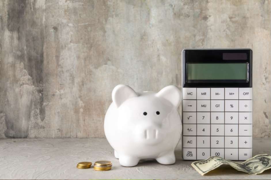 賃貸アパートの更新料のコストを計算するイメージ。白い豚の貯金箱と電卓、そして現金。